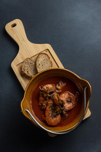 Een kom garnalenstoofpot met brood op een zwarte tafel