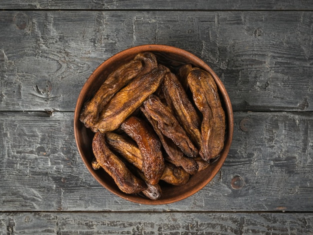 Een kom gedroogde bananen op een zwarte houten tafel Heerlijke natuurlijke fruitsnack Flat lay