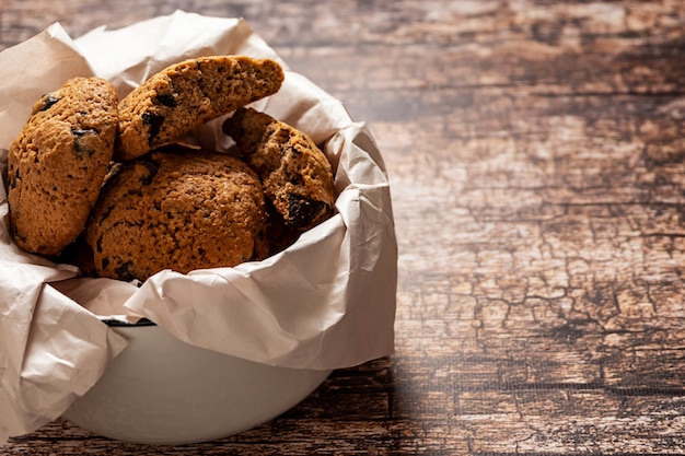 Een kom met zelfgemaakte chocoladekoekjes op de vintage houten achtergrond, met kopie ruimte