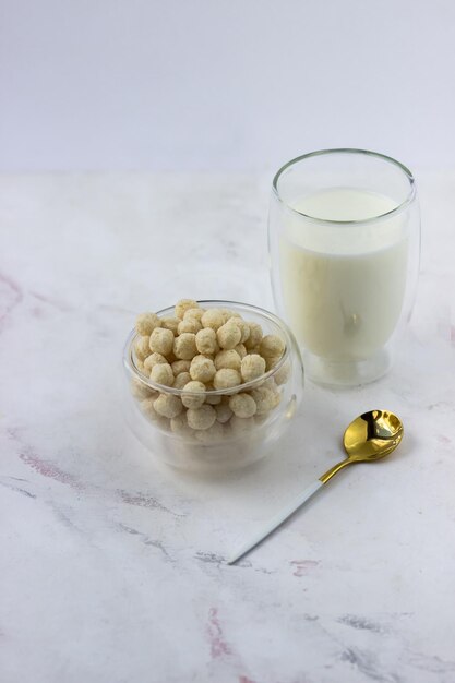 Een kom ontbijtgranen en een glas melk op een witmarmeren tafel Instant cornflakes