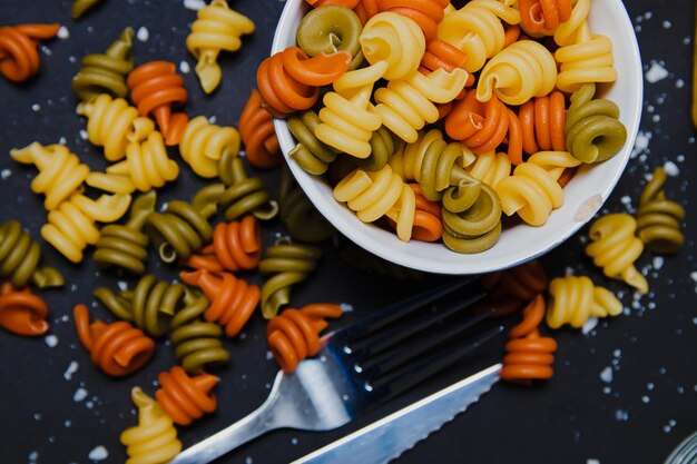 Een kom pasta met een vork ernaast