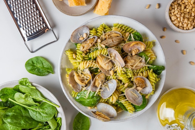 Een kom pasta met schelpen en citroenen op tafel.