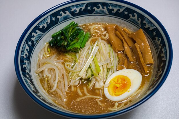 Een kom ramen met een blauwe rand en een paar groene groenten.