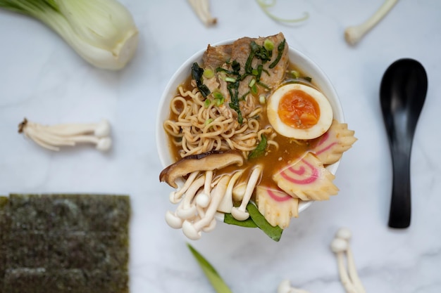 Een kom ramensoep met alle ingrediënten boven een marmeren tafel