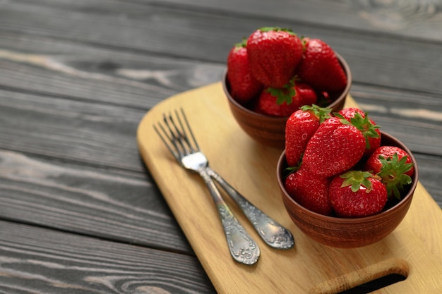 Een kom rode, sappige aardbeien op rustieke houten tafel Gezond en dieet snack food concept