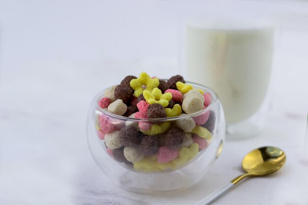 Een kom snacks in de vorm van een bal, harten en bloemen op een witmarmeren tafel Ontbijtgranen en een glas melk