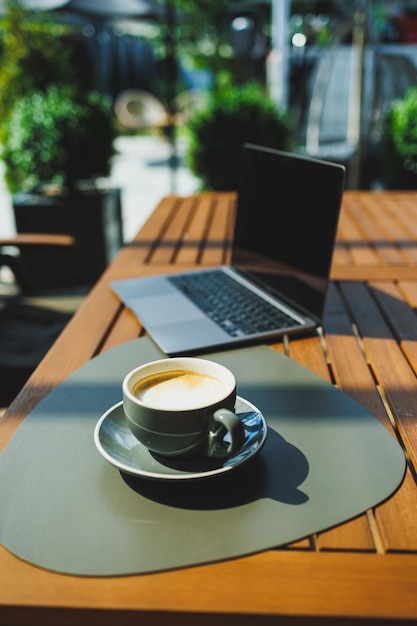 Een kop aromatische koffie op de achtergrond van een laptop op een zomerterras Werk in een café Online werken op afstand