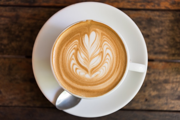 Een kop hete latte kunstkoffie op houten lijst