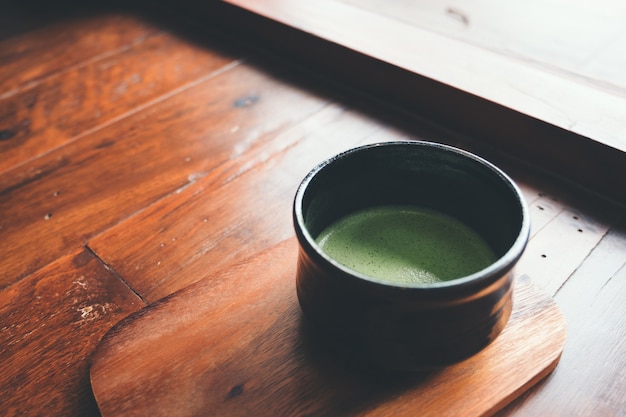 Een kop hete matcha latte op houten vloer