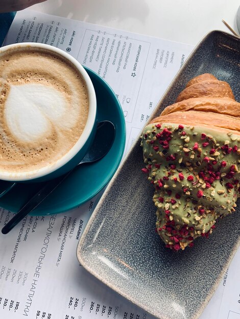 Foto een kop koffie en een gebakje op een tafel met een bord erop.