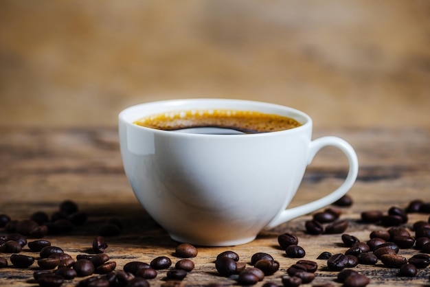 Een kop koffie met koffiebonen op een houten achtergrond met een donkere toon