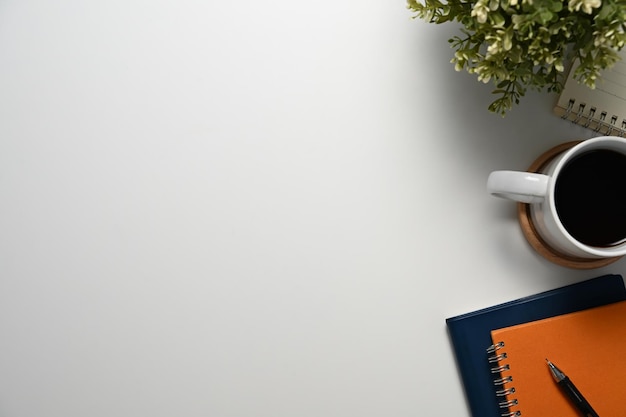 Een kop koffie notitieboek en potplant op een witte werktafel