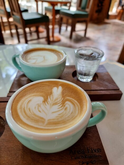 Een kop latte koffie met drinkwater op een houten bord