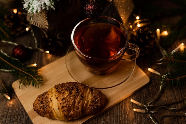 Een kop thee met croissant bij de kerstboom. Oudejaarsavond thuis met het gezin.