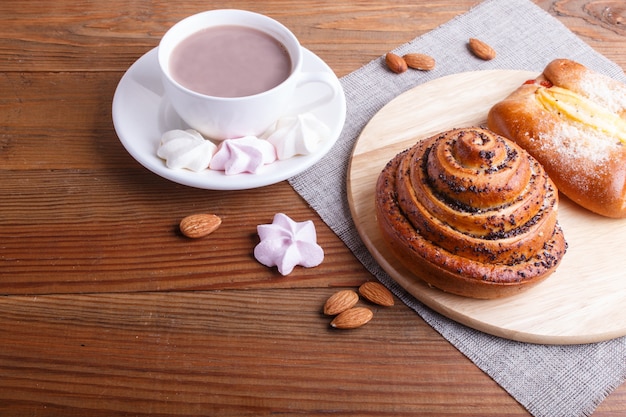 Een kop warme chocolademelk en broodjes op bruine houten oppervlak.