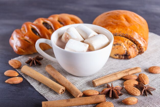 Een kop warme chocolademelk met marshmallow, broodjes, amandelen en specerijen