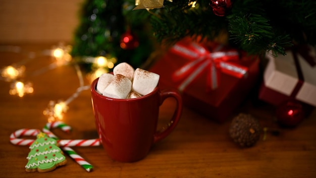 Een kop warme chocolademelk met marshmallow op houten tafel met kerstboom en decor