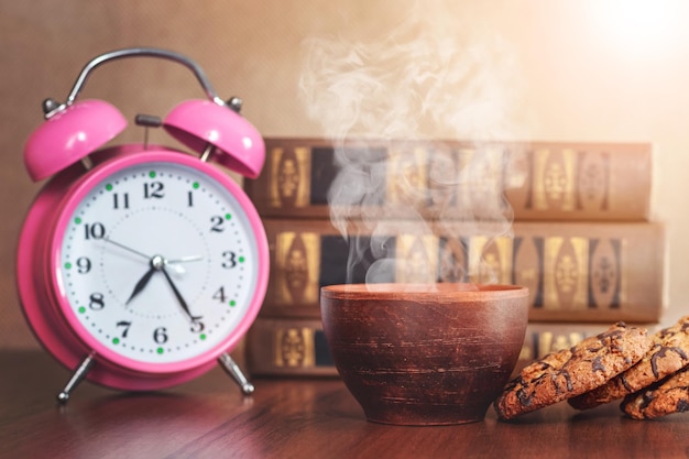 Een kop warme koffie en koekjes in de buurt van boeken en een klok in een bibliotheek of studeerkamer