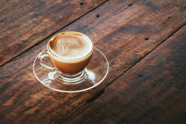 een kop warme koffie in een glazen koffiekopje op oude houten tafel