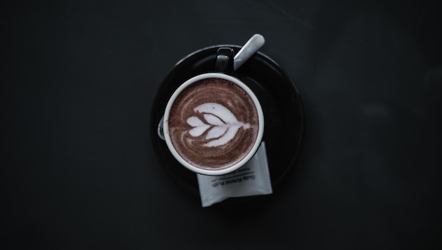 Foto een kop warme koffie latte op de zwarte tafel