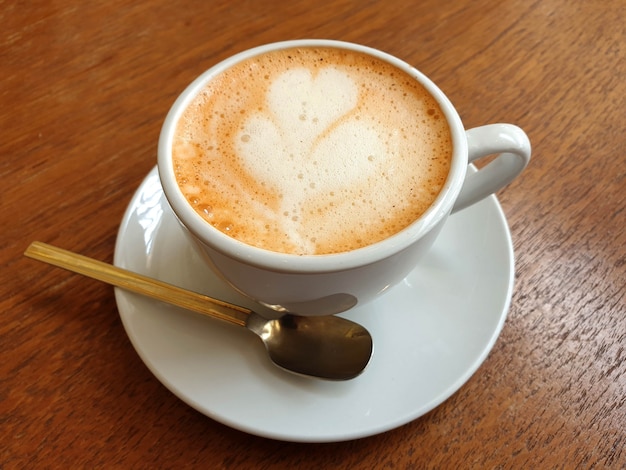 Een kop warme latte art koffie op een houten tafel