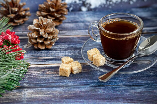 Een kopje aromatische koffie met bruine suiker, kerstversiering, takken van een kerstboom. Vakantieconcept Nieuwjaar. Op een houten achtergrond. Ruimte kopiëren.