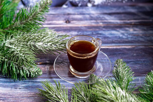 Foto een kopje aromatische koffie met bruine suiker, kerstversiering, takken van een kerstboom. vakantieconcept nieuwjaar. op een houten achtergrond. ruimte kopiëren.