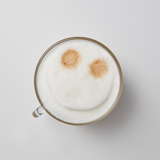 Een kopje geurige cappuccino met een lachend gezicht op een grijze achtergrond met een kopie van de ruimte. Top