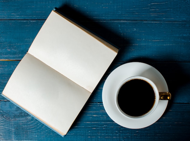 Een kopje geurige koffie en een boek liggen op een houten achtergrond.