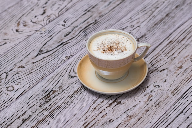 Een kopje geurige koffie met melk en kaneel op een houten tafel