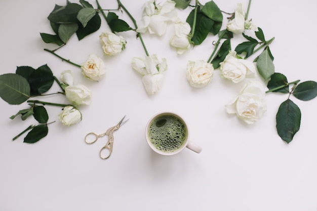 Een kopje groene thee met witte rozen op wit uitzicht van bovenaf. Flatlay, bovenaanzicht, kopieerruimte.