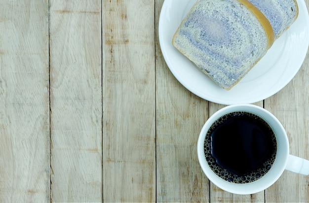 Een kopje koffie en brood op witte plaat op hout achtergrond