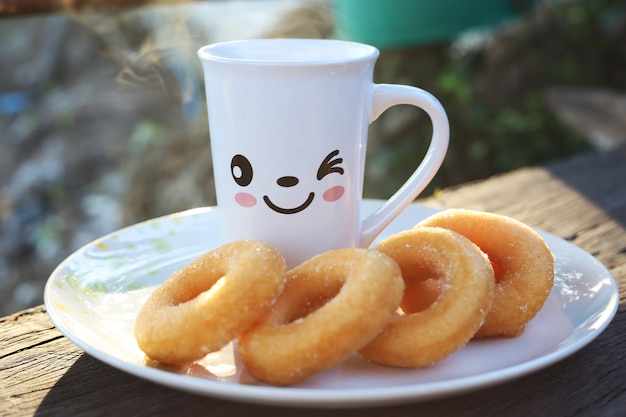 Een kopje koffie en donuts op houten tafel in de ochtend
