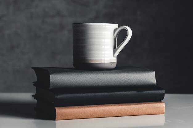 Een kopje koffie in de buurt van stapel boeken op grijze achtergrond
