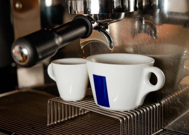 Een kopje koffie in een koffiezetapparaat voor het inschenken van koffiebarista die koffie maakt in een café