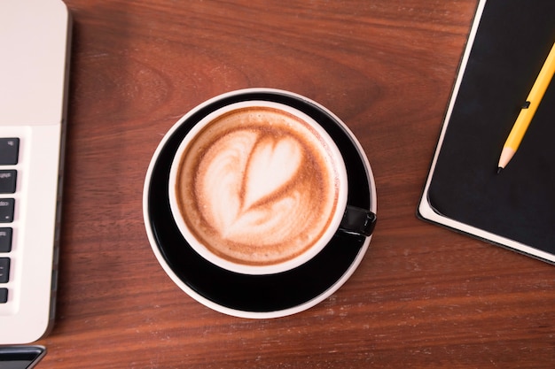 Een kopje koffie met hartvorm op houten tafel