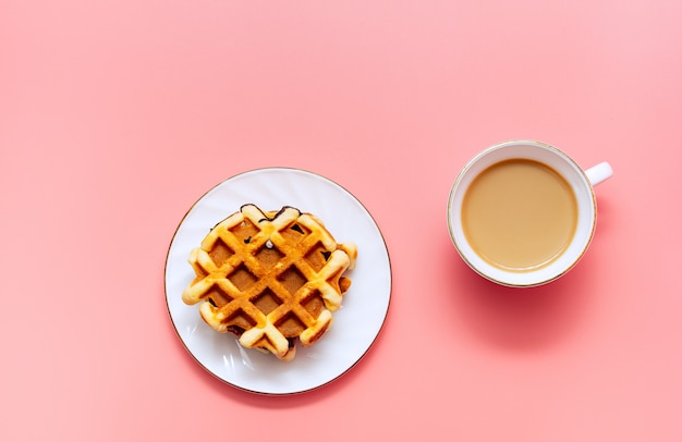 Een kopje koffie met melk en zelfgemaakte wafels op een roze achtergrond. Lekker ontbijt. minimalisme