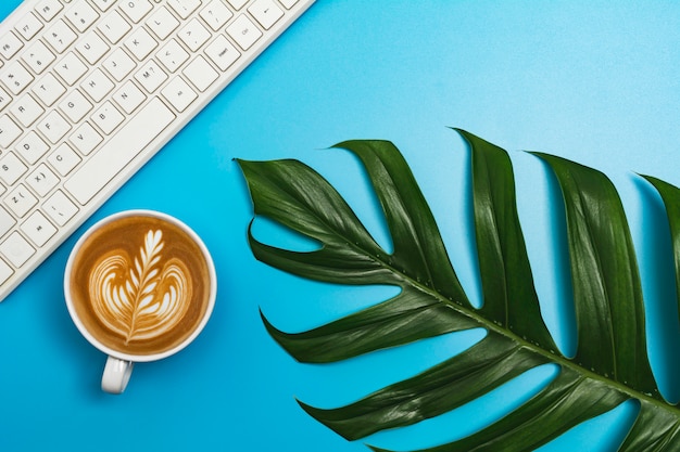 Een kopje koffie met toetsenbord en kopie ruimte op blauwe tafel. Bureau en drankje concept.