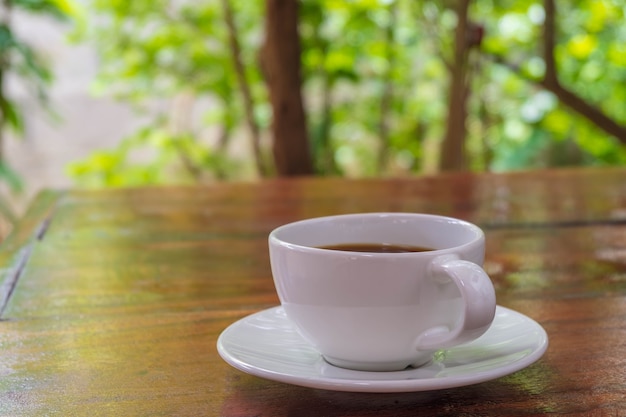 Een kopje koffie op een houten tafel in de ochtend met de late ochtendzon. Een kopje koffie op een houten tafel in de ochtend met de late ochtendzon.