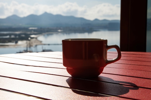Een kopje koffie op een rode tafel Uitzicht op het meer zee oceaan rivier Shadows backlight