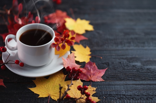 een kopje koffie op een tafel met herfstbladeren