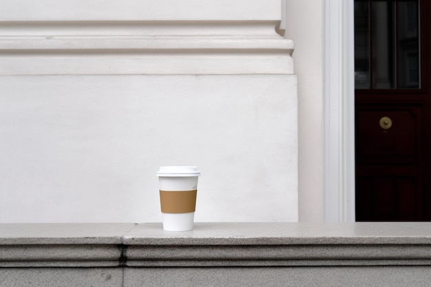 Een kopje koffie staat op een richel voor een raam.