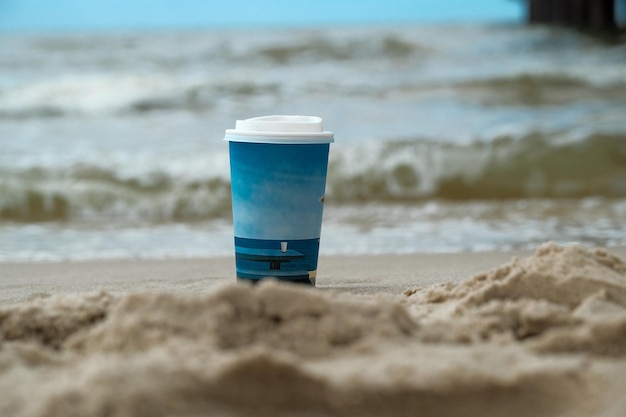 Een kopje koffie staat op het zand van de zee tegen de achtergrond van een onweersbui Een kopje zwarte koffie staat op het zandstrand op een zonnige dag Ontspanning of loungemuziekconcept