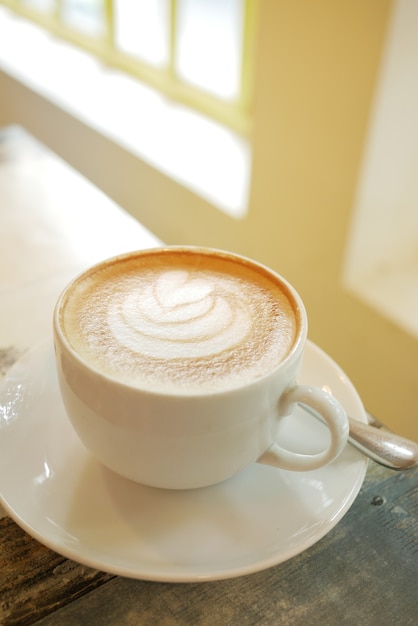 Een kopje late koffie met een bloemvormig ontwerp bovenop in café