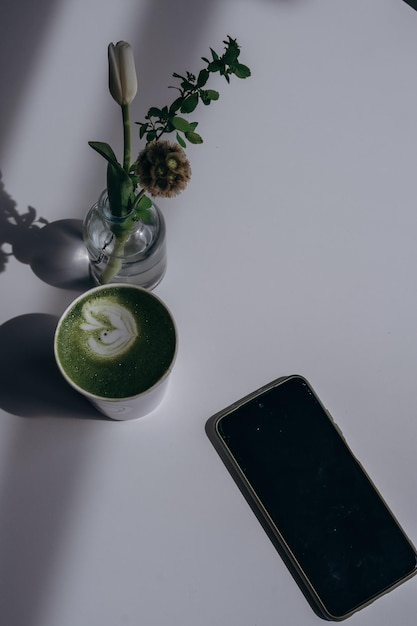 Een kopje matcha latte met een bloem op tafel