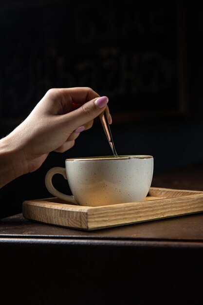 Een kopje matcha latte met een lepel op een houten dienblad