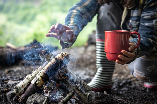 Een kopje met een warm drankje tijdens het wandelen in het bos bij het vuur.