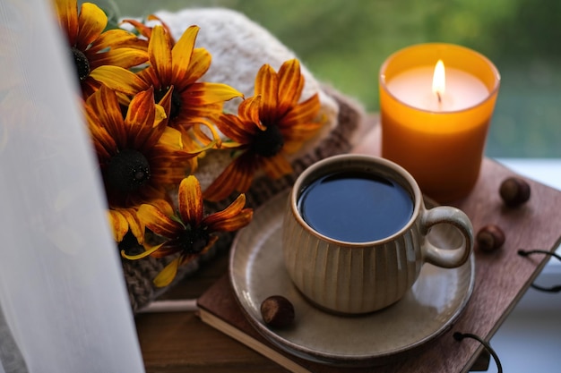 Een kopje thee, een kaars en oranje bloemen op een achtergrond van de herfstnatuur Herfststilleven