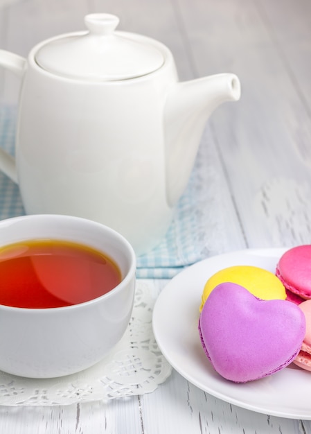 Een kopje thee en theepot met macaron koekjes