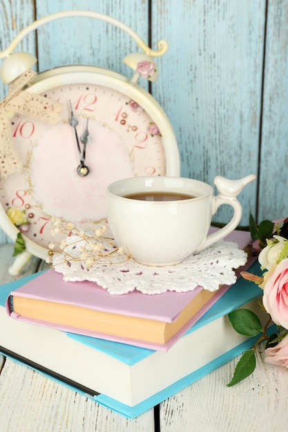Een kopje thee met boeken en bloemen op een houten achtergrond